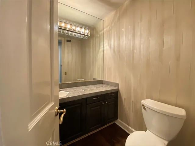 a bathroom with a granite countertop toilet sink and mirror