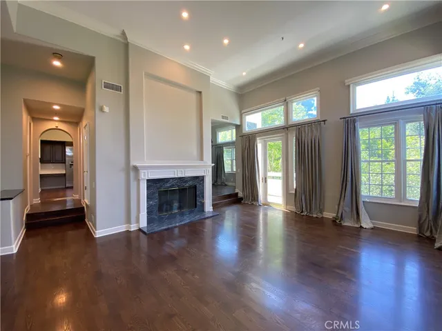 an empty room with wooden floor fireplace and windows