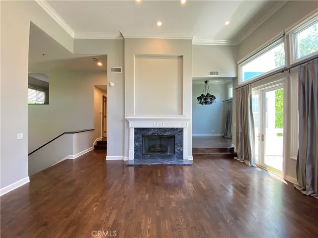 an empty room with wooden floor a fireplace and windows