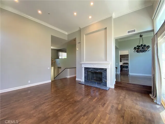 an empty room with wooden floor fireplace and staircase