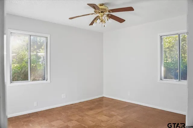 an empty room with windows and fan