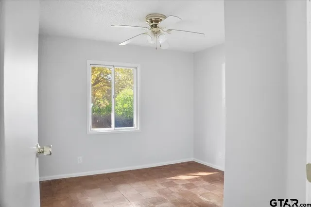 an empty room with a window and a ceiling fan