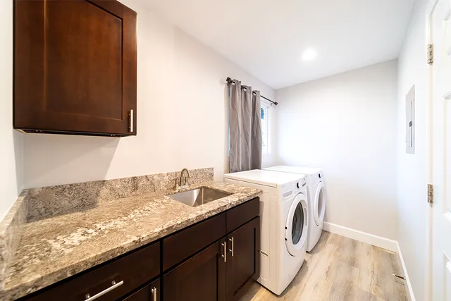 a utility room with granite countertop cabinets washer and dryer