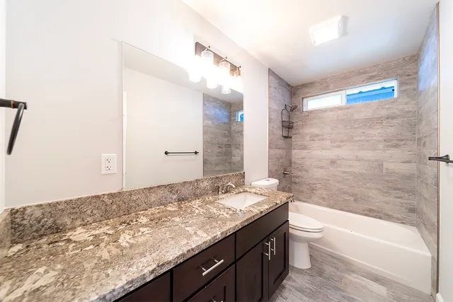 a bathroom with a granite countertop sink a toilet and bathtub