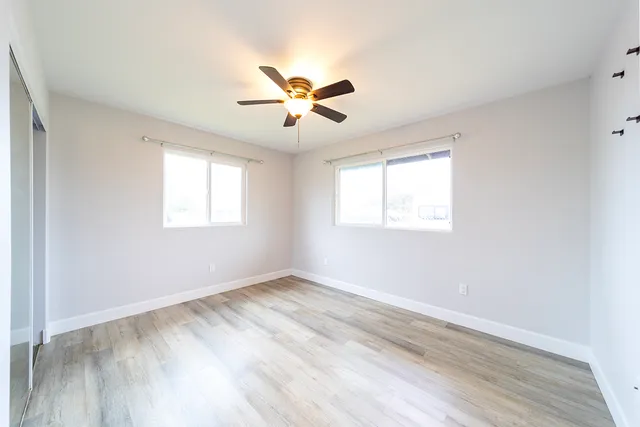 a view of empty room with wooden floor and fan