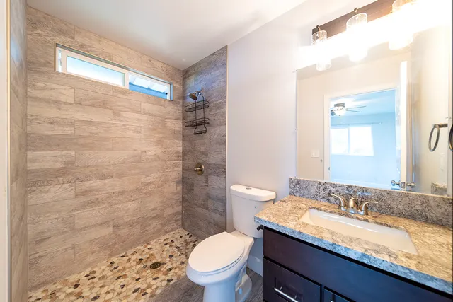 a bathroom with a granite countertop sink toilet and shower
