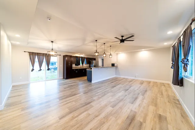 a view of a living room and kitchen with stainless steel appliances wooden floor