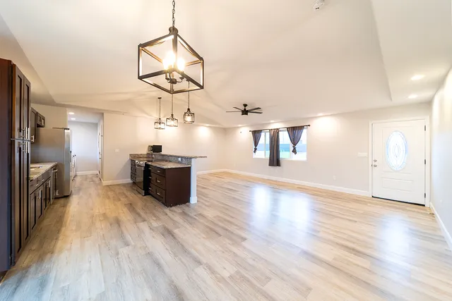 a living room with stainless steel appliances kitchen island granite countertop a sink a counter space and cabinets