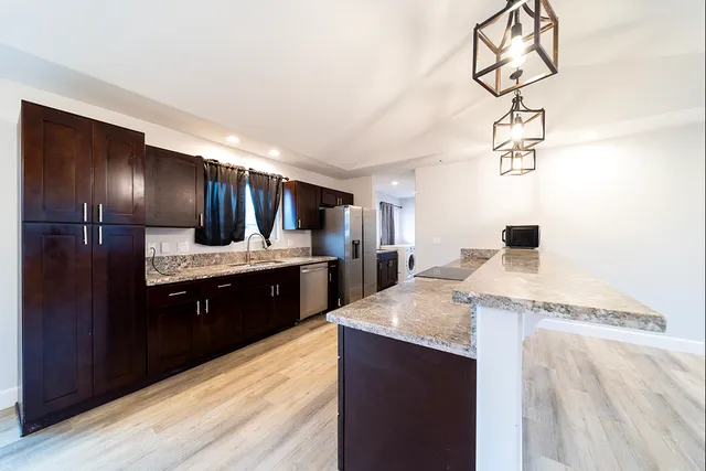a large kitchen with a chandelier stainless steel appliances a sink and counter space