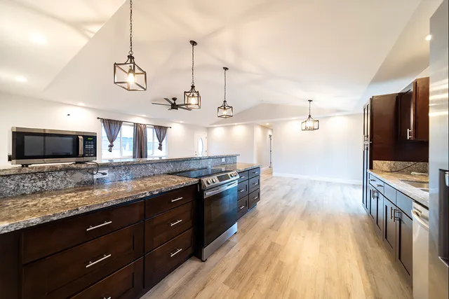 a large kitchen with stainless steel appliances granite countertop a stove and a wooden floors