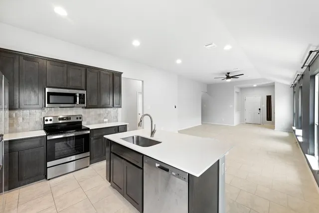 a kitchen with stainless steel appliances a sink stove refrigerator and cabinets