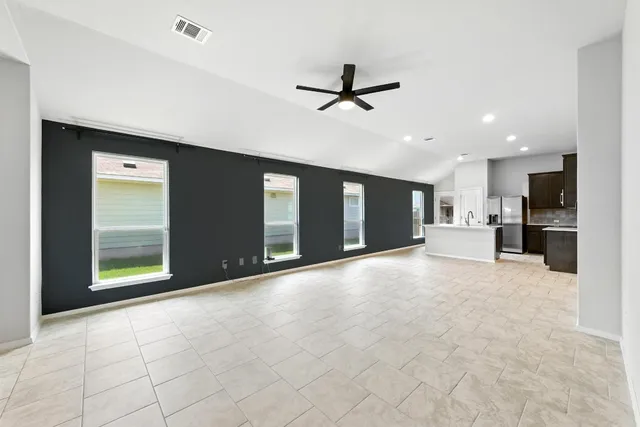 a view of an empty room with a window and kitchen view