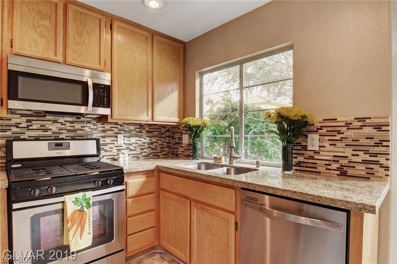 2647 Ridgewater Circle Henderson, NV 89074 - Photo 3 of 26 Granite countertops and wood cabinetry surround a central window overlooking the yard.
