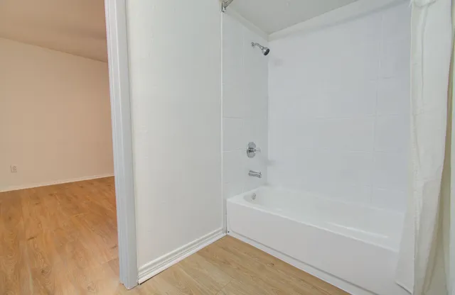 a white bath tub sitting next to a shower