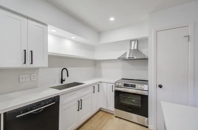 a kitchen with cabinets stainless steel appliances and wooden floor