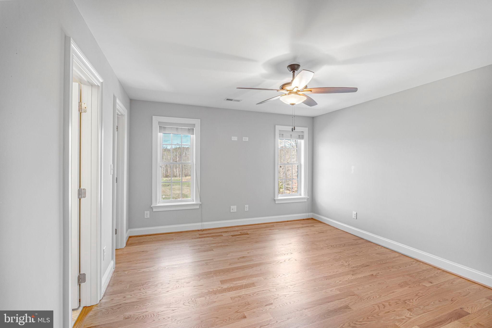 1185 Belle Meade Road Bumpass, VA 23024 - Photo 36 of 116 an empty room with wooden floor chandelier fan and windows