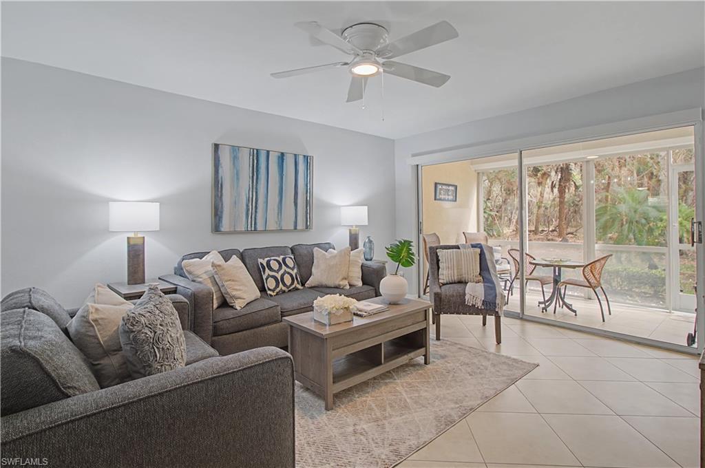 741 Landover Circle, Unit 102 Naples, FL 34104 - Photo 15 of 27 a living room with furniture and a large window with garden view