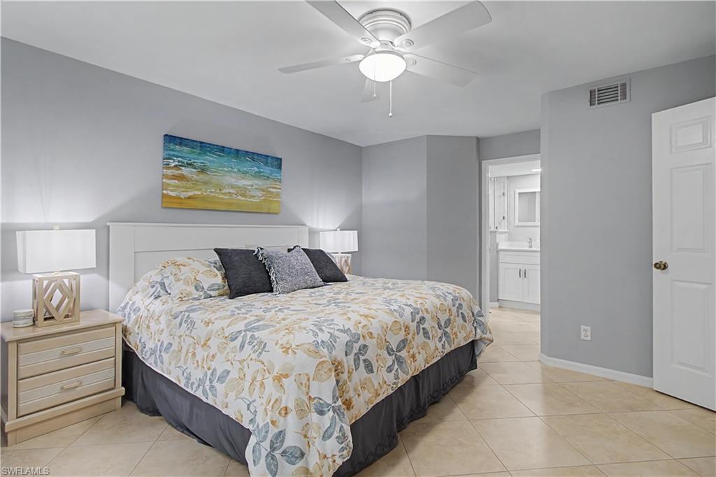 741 Landover Circle, Unit 102 Naples, FL 34104 - Photo 18 of 27 a bedroom with bed and a chandelier