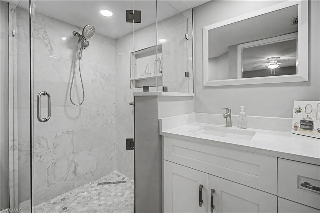 741 Landover Circle, Unit 102 Naples, FL 34104 - Photo 19 of 27 a bathroom with a granite countertop sink vanity mirror and shower