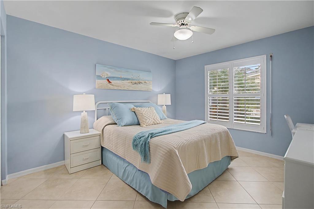 741 Landover Circle, Unit 102 Naples, FL 34104 - Photo 21 of 27 a bedroom with a bed and a chandelier