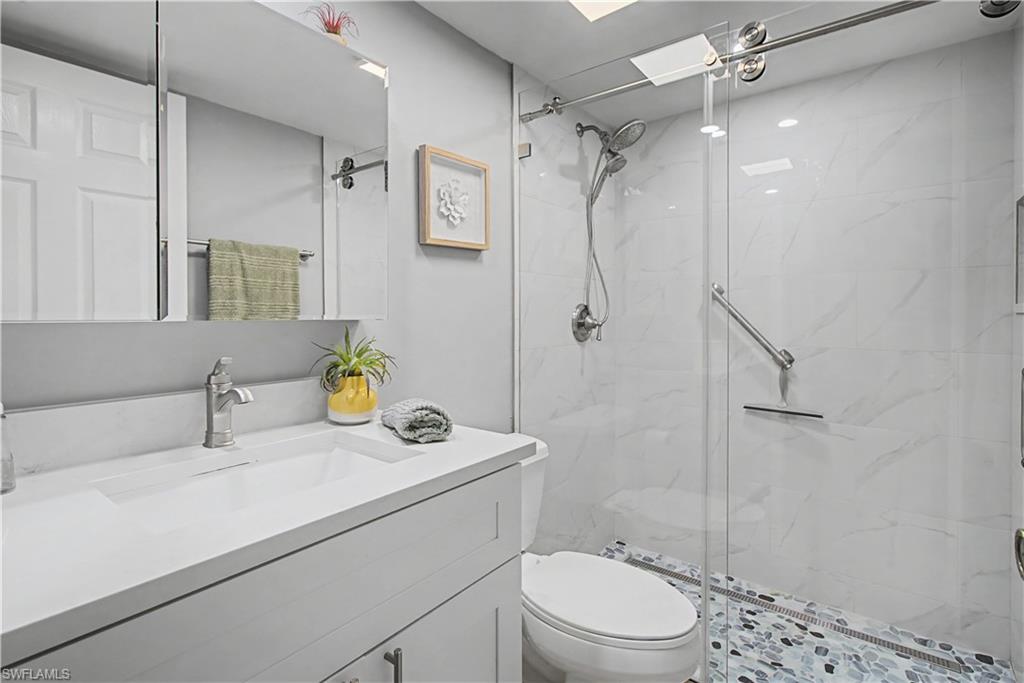741 Landover Circle, Unit 102 Naples, FL 34104 - Photo 22 of 27 a bathroom with a sink a toilet and shower
