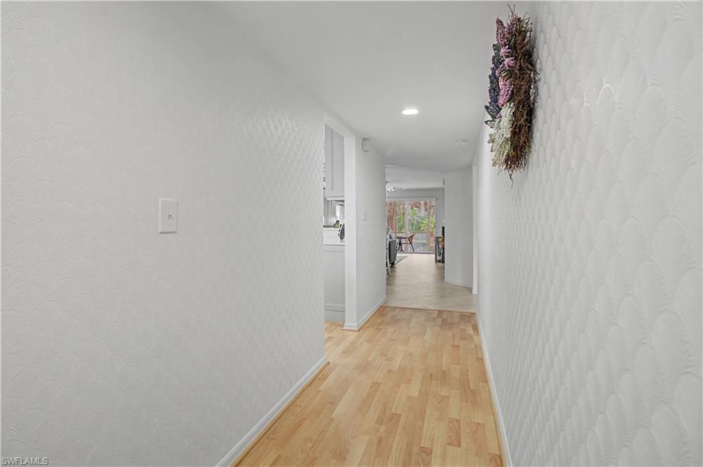 741 Landover Circle, Unit 102 Naples, FL 34104 - Photo 6 of 27 a view of a hallway with wooden floor and a bathroom