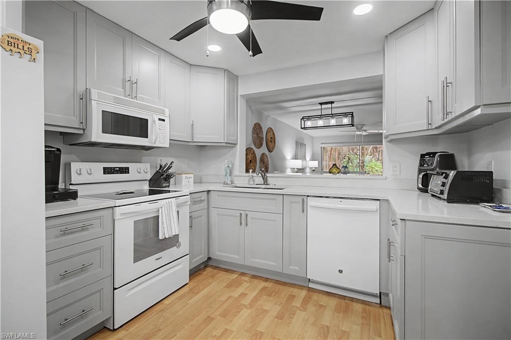 741 Landover Circle, Unit 102 Naples, FL 34104 - Photo 8 of 27 a kitchen with white cabinets stainless steel appliances and sink