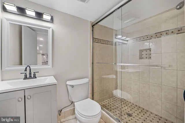 a bathroom with a toilet a sink a shower and a mirror