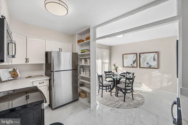 a kitchen with stainless steel appliances a refrigerator a stove a dining table and chairs with wooden floor