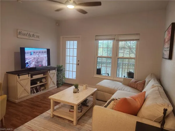 a living room with furniture a flat screen tv and a floor to ceiling window