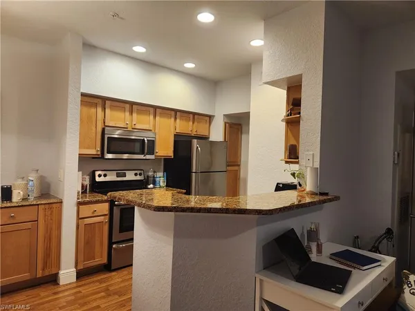a kitchen with stainless steel appliances kitchen island granite countertop a stove a sink and a refrigerator