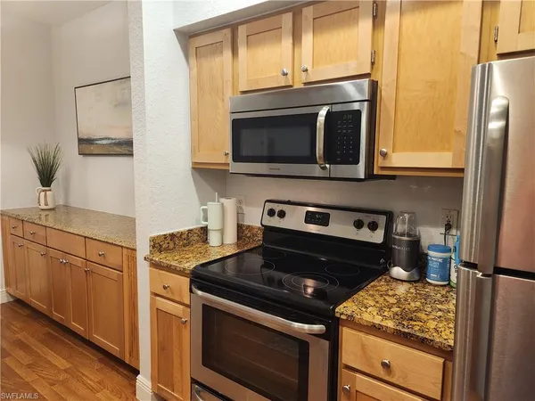 a kitchen with granite countertop cabinets stainless steel appliances and wooden floor