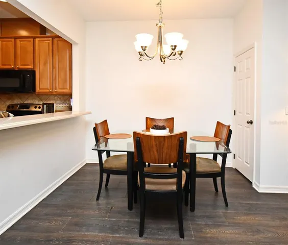 a dining room with wooden floor a chandelier a wooden table and chairs