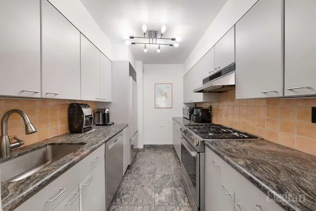 a kitchen with granite countertop stainless steel appliances a sink a stove and cabinets