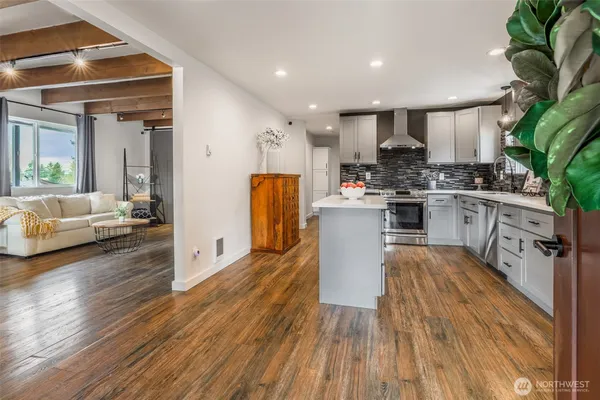 a kitchen with stainless steel appliances granite countertop wooden floors a stove and a refrigerator