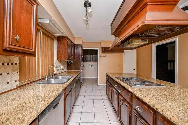 a kitchen with stainless steel appliances granite countertop a sink a stove and a wooden cabinets