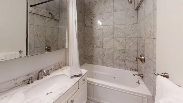 a white bath tub sitting next to a white sink and vanity