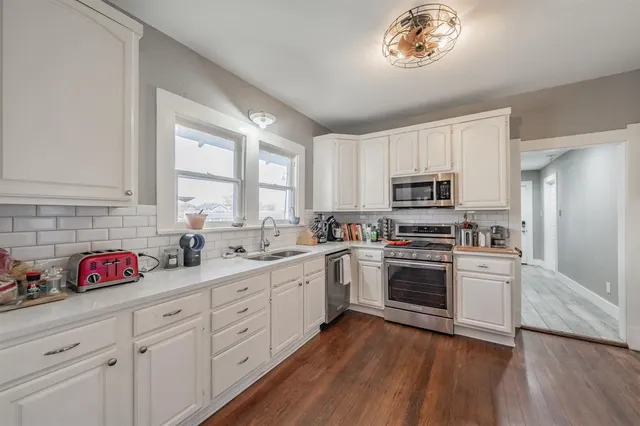 a kitchen with white cabinets white stainless steel appliances and sink