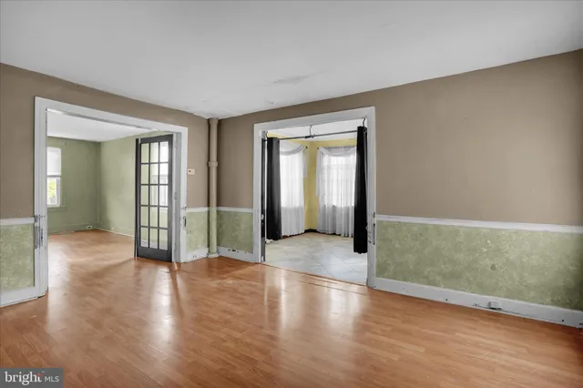 an empty room with wooden floor and mirror