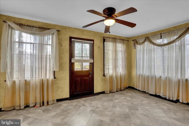 an empty room with ceiling fan and windows