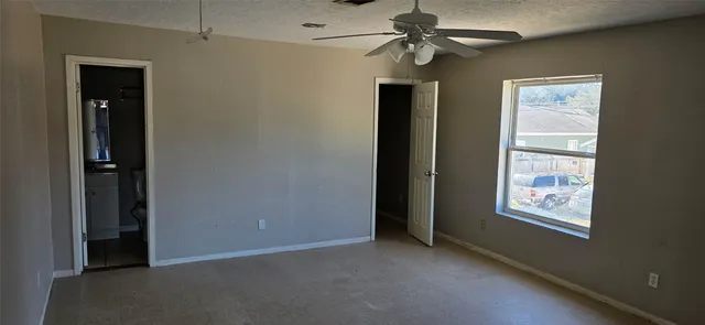 an empty room with windows and fan