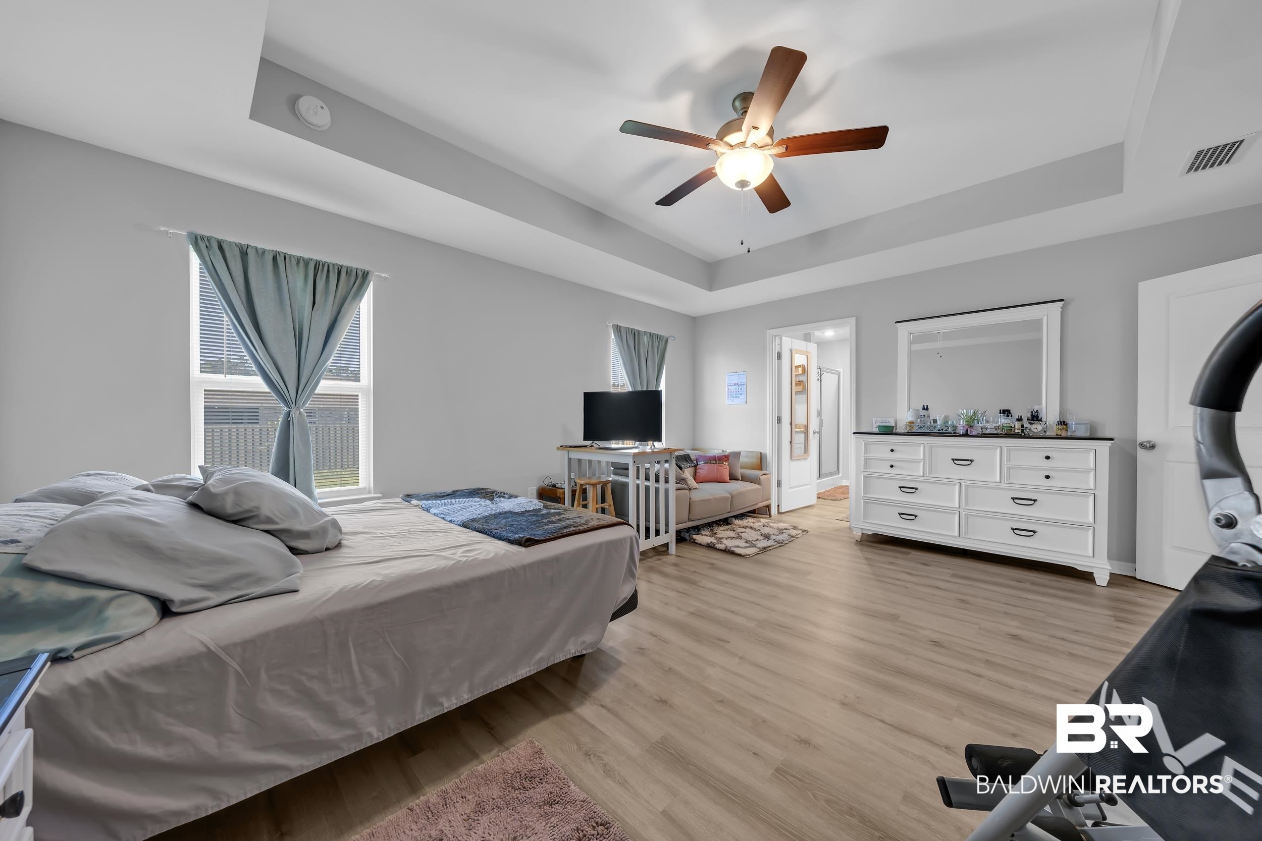 1228 Caper Avenue Foley, AL 36535 - Photo 20 of 54 Spacious room featuring wood-finish flooring, a tray ceiling, and a ceiling fan with integrated lighting