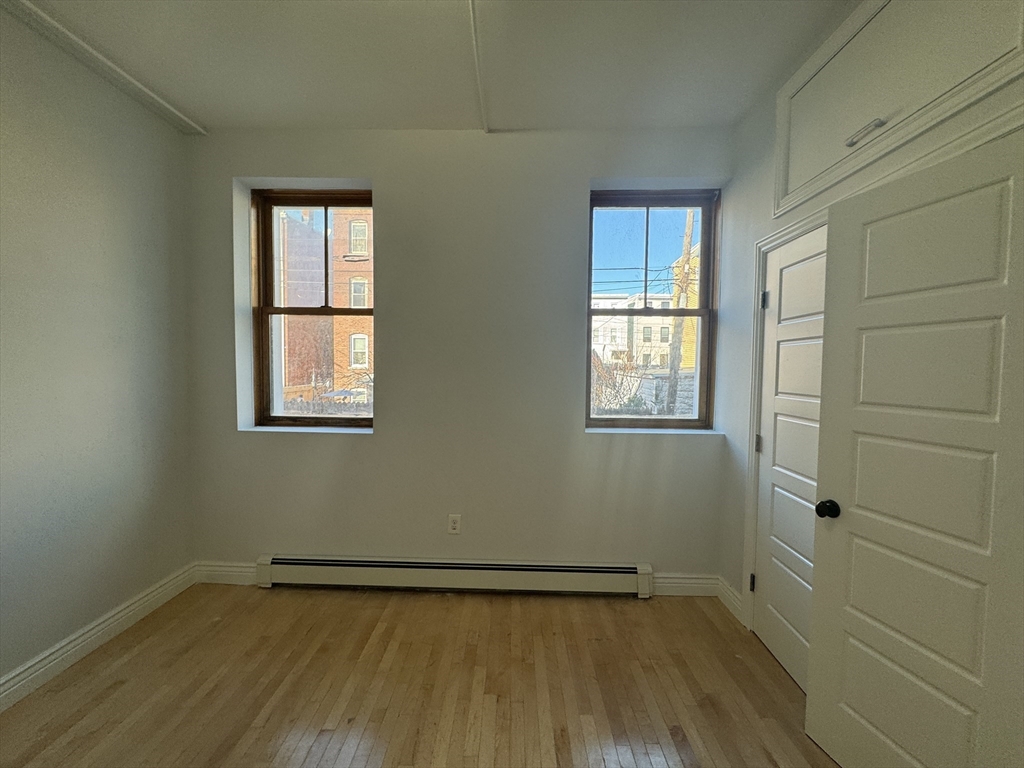212 Chelsea Street, Unit 1 Boston, MA 02128 - Photo 4 of 24 a view of an empty room with wooden floor and a window