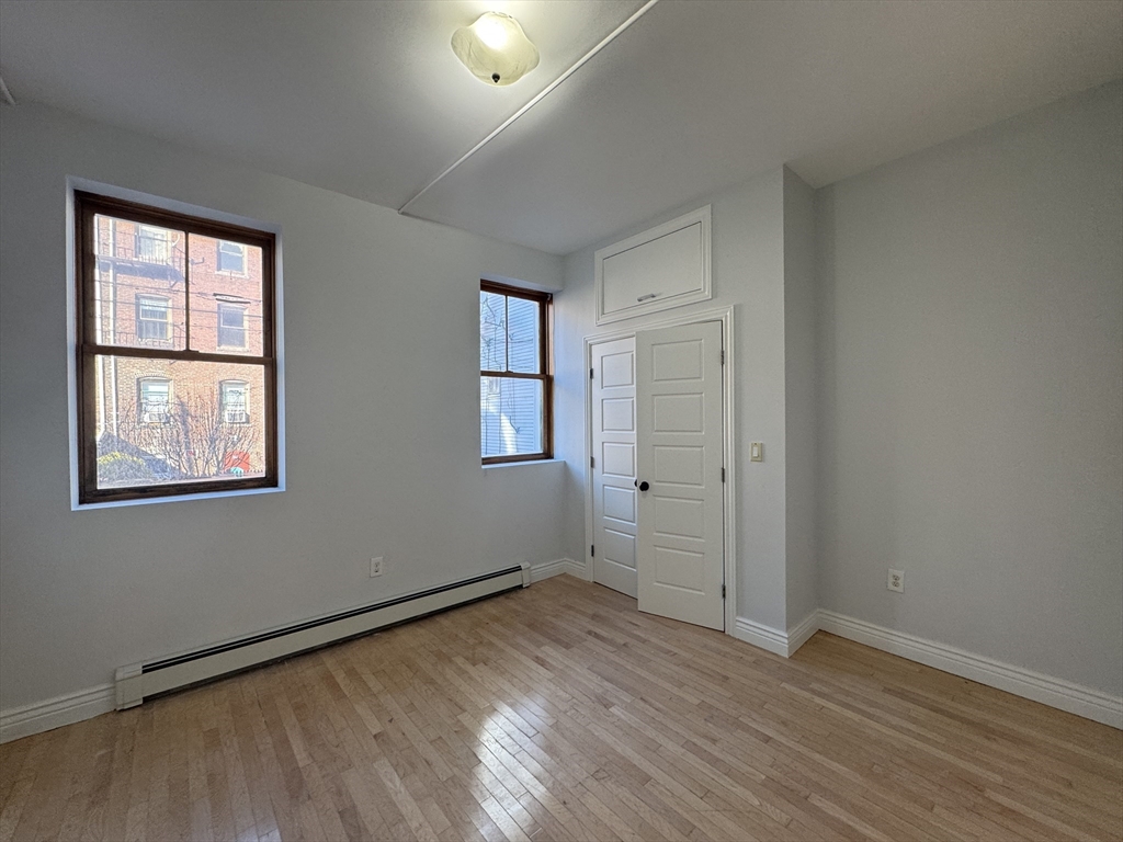 212 Chelsea Street, Unit 1 Boston, MA 02128 - Photo 6 of 24 an empty room with wooden floor and windows