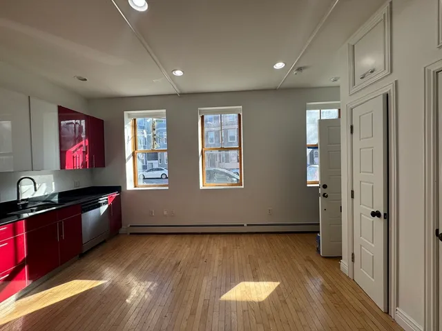 a view of a kitchen with a refrigerator and wooden floor