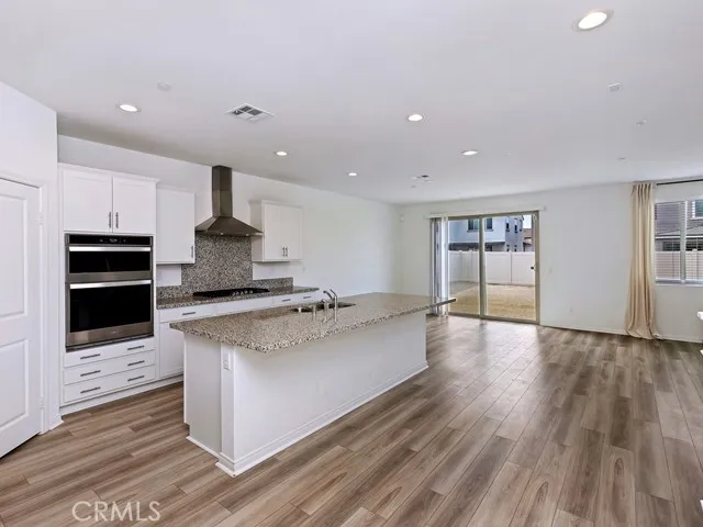 a large kitchen with stainless steel appliances a large counter top and a wooden floor