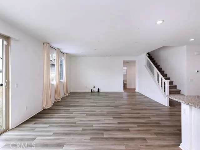 a view of a living room with wooden floor and stairs