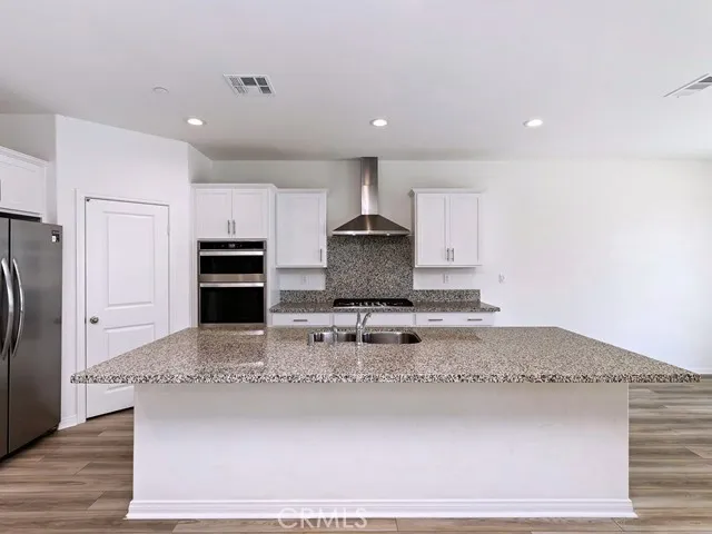 a kitchen with kitchen island granite countertop a stove a refrigerator and a sink