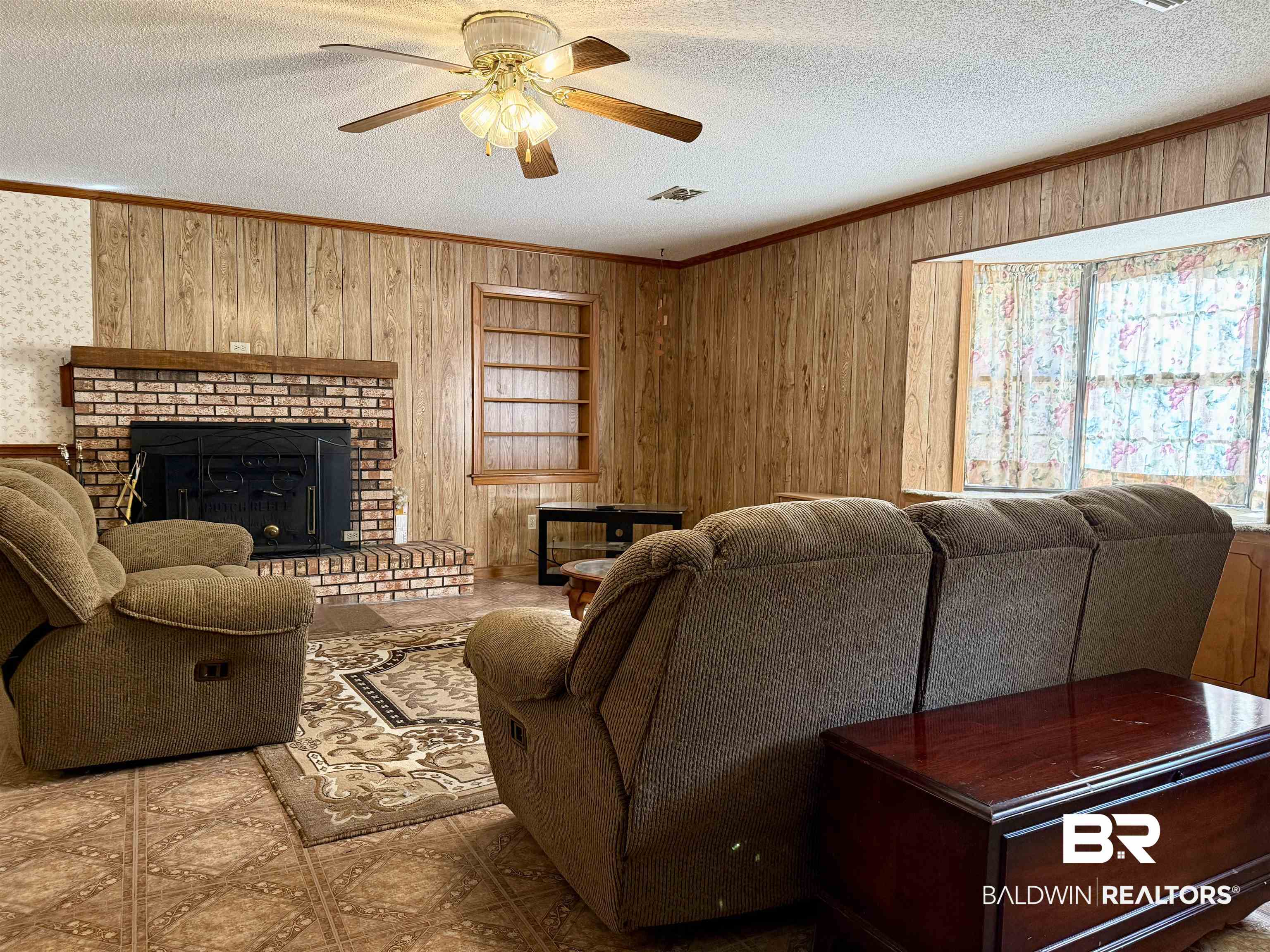 98 Evans Avenue Brewton, AL 36426 - Photo 6 of 18 Living room with ornamental molding, wood walls, a fireplace, a textured ceiling, and ceiling fan
