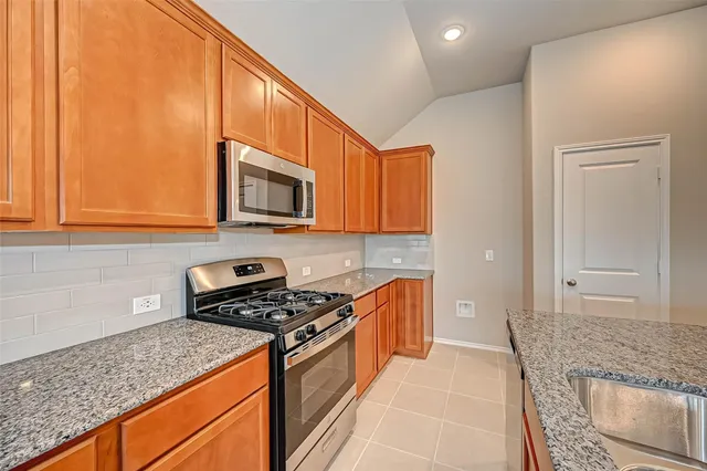 a kitchen with stainless steel appliances granite countertop a stove a sink and a microwave